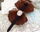 Gold-tone Noah × Timex Boatswain watch with white Roman numeral dial and black leather strap, photographed on nautical charts and woven wicker.