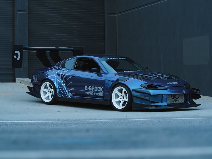 Blue drift car featuring G-Shock and Toyo Tires graphics parked outside an industrial building.