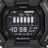 Casio G-Shock Mudman GDG-B100 watch with red and white digital display against a rugged mountain landscape.