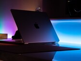 Half-open MacBook in a dark room, light spilling from the gap onto the desk
