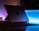 Half-open MacBook in a dark room, light spilling from the gap onto the desk