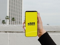 A hand holding a smartphone with the word eSIM large on a yellow screen.