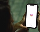 Woman holding a smartphone in both hands, the display shows the Instagram start screen