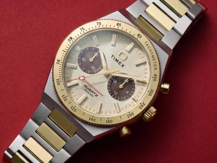 Close-up of the Timex Q Timex Continental Chronograph TW2Y92300 worn on a wrist, showing its gold-tone dial, brown sub-dials, tachymeter bezel, and two-tone stainless-steel bracelet.