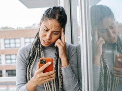 A woman looks at her smartphone with a serious expression