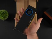 A person holding the Intel Arc Pro B50 low-profile workstation GPU with a blower-style cooler, shown against its packaging box. (Image source: ETA Prime via YouTube)