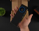 A person holding the Intel Arc Pro B50 low-profile workstation GPU with a blower-style cooler, shown against its packaging box. (Image source: ETA Prime via YouTube)