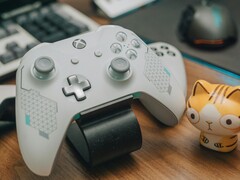 White Xbox controller resting on a wooden desk beside a small cat figurine (Image source: FOX ^.ᆽ.^= ∫ via Pexels)