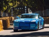 The Jaguar Type 01 EV in Blue Exuberant Modernism Camouflage zooming past the starting grid in Goodwood Hill Climb