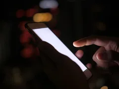 スマートフォンの画面が暗闇で光っている様子